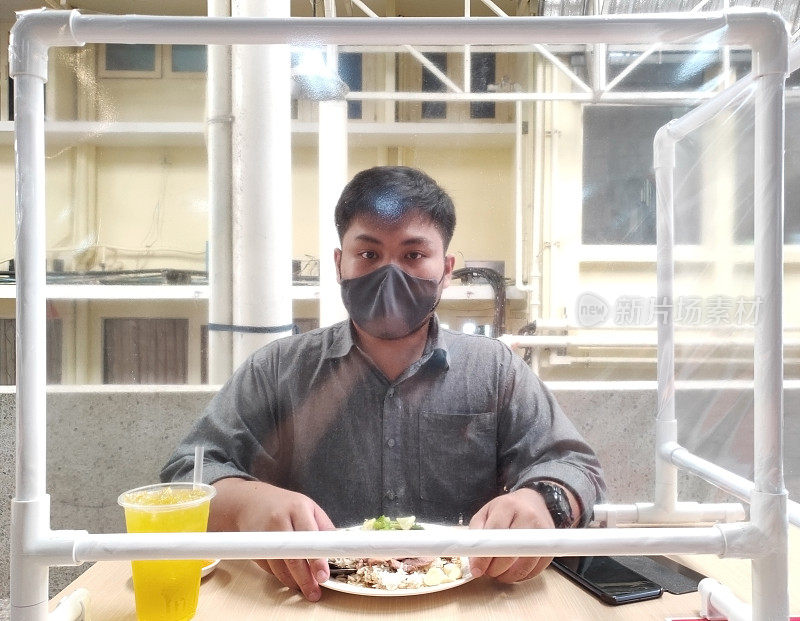 Soft focus on Partition on front of man wearing masks are eating lunch with Partition for prevent airaircontamination in viral epidemic situation, Social Distancing and New normal concept .软focus on Partition on front of man masks为防止病毒流行情况下的空气污染、社交距离和新常态概念。